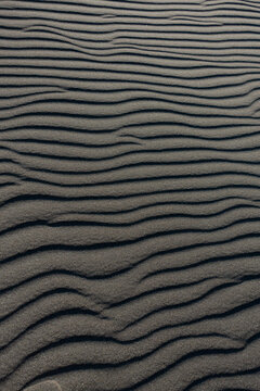 Abstract sand ripples texture with dramatic shadows on desert dunes