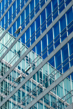 Steel framework and glass facade create layered geometric patterns, showing modern architecture through structural lines and reflective urban building surfaces