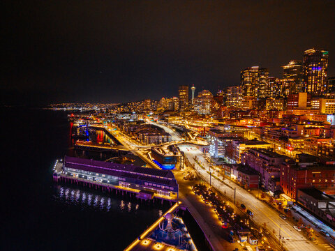 Seattle downtown skyline and waterfront with illuminated ferris wheel reflecting on Elliott Bay at night aerial view. g.