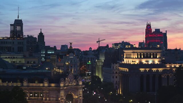 High angle vantage point from Palacio de Cibeles terrace showing Madrid downtown architecture with construction crane silhouetted at beautiful pink twilight sunset in Spain, urban planning b-roll.