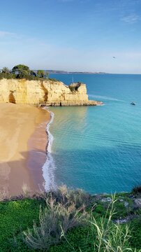 golden sand beach and limestone cliffs in algarve coast portugal with clear turquoise sea water