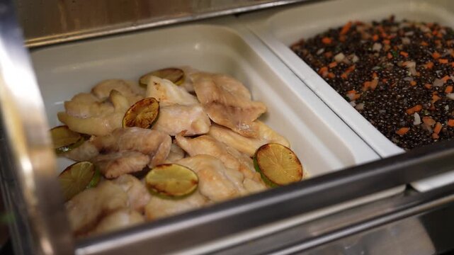 Motion view of buffet style restaurant food with fish and other dishes displayed in serving trays.