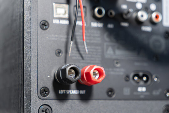 A close up view of audio speaker binding posts with bare copper wire ends prepared for connection to a home sound system amplifier to enable high fidelity music playback equipment