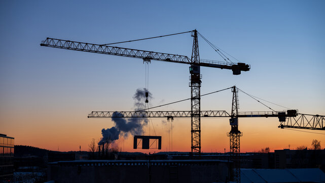 View of construction cranes silhouetted against a vibrant sunset sky at a building site in Vilnius, Vilnius County, Lithuania.