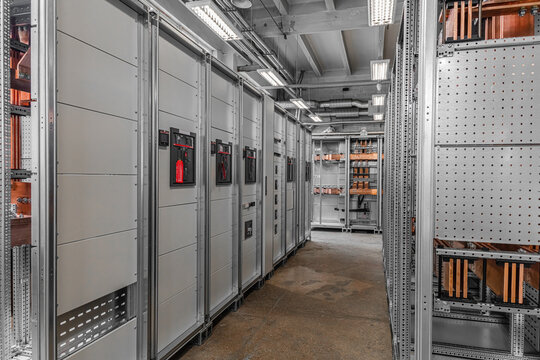 View of industrial electrical switchgear cabinets with copper busbars and control panels in a power distribution room in Latvia.