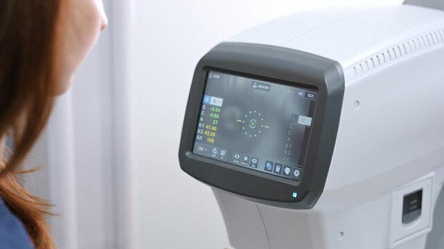 Female optometrist performs an eye test on a young girl using specialized equipment in a well-lit clinic environment