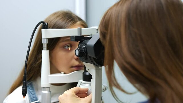 Young girl undergoing eye examination with optometrist using a phoropter in a modern clinic, medical equipment and supplies visible in the background
