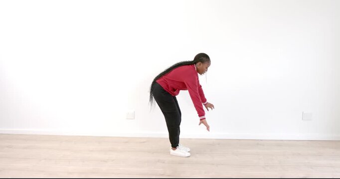 Young girl in red sweater stretching indoors, focusing on fitness and flexibility