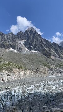 authentic alpine landscape with glacier and rock peaks under blue sky- vertical footage