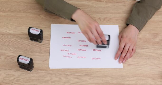 Woman office worker tests freshly refilled rubber stamp on table. Female applies numerous precise impressions to plain white sheet. Time lapse