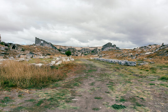 View of the ancient ruins of Aizonai with scattered stone structures and archaeological remains under a cloudy sky in Cavdarhisar, Kutahya, Turkiye.