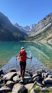 woman hiker with backpack standing at clear alpine mountain lake active travel freedom- vertical video