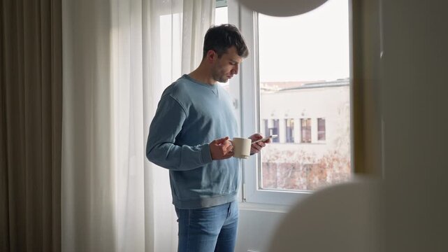 Man standing by window using phone