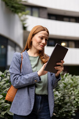Confident businesswoman using digital tablet in front of modern office building © Novak