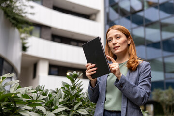 Confident businesswoman using digital tablet in front of modern office building © Novak
