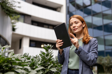 Confident businesswoman using digital tablet in front of modern office building © Novak