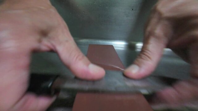 Hands sharpening a small Japanese deba knife on a whetstone