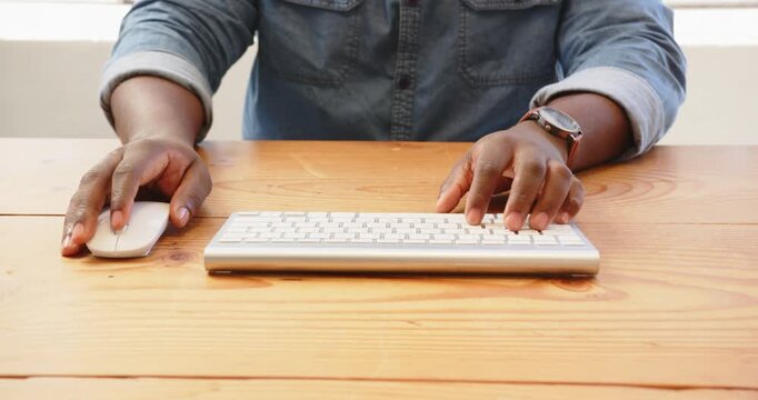 Hands typing on wireless keyboard at wooden desk, focusing on work