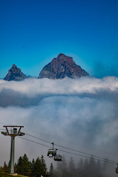 View of the Swiss Alps rising above a thick layer of clouds with a cable car system in the foreground in Airolo, Ticino, Switzerland.