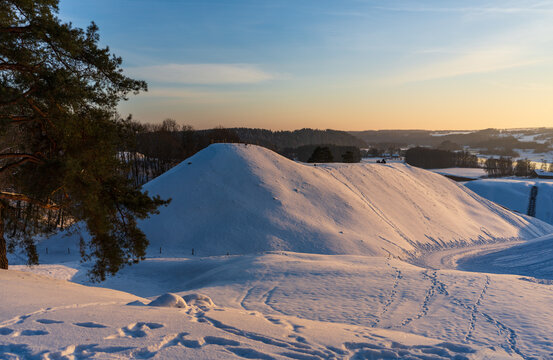 View of the snow-covered mounds at the Kernave Archaeological Site during a golden sunset in Kernave, Vilnius County, Lithuania.