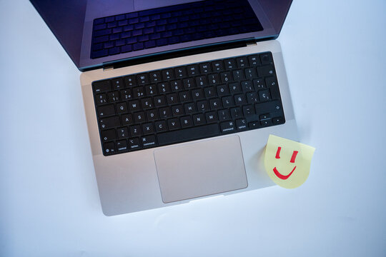 Laptop with a smiley face sticky note bringing positivity and happiness to remote work and online communication