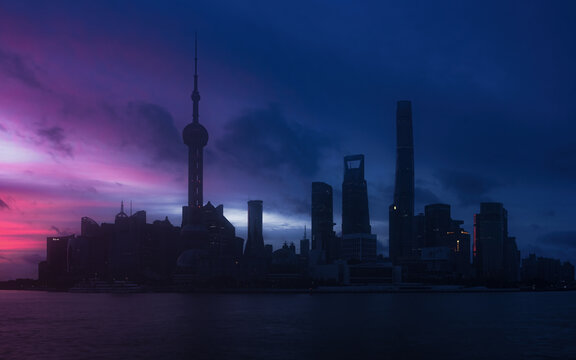 View of the Shanghai skyline featuring the Oriental Pearl Tower silhouetted against a vibrant purple and pink twilight sky over the Huangpu River in Shanghai, Shanghai, China.