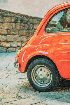 Rear side of a red classic small italian car in a street.
