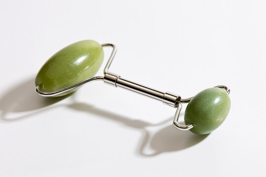 Green jade facial roller on white background