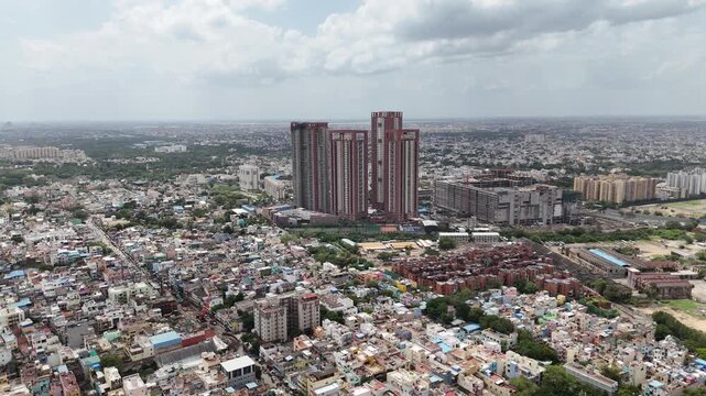 Wide aerial panorama of Perambur, Chennai, featuring the distinctive SPR City residential towers rising above a densely populated urban landscape. Colorful homes, apartment developments, constructions