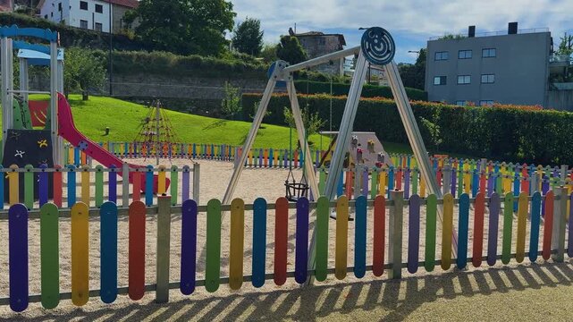 A smooth panning shot capturing a brightly lit, empty children's playground on a sunny day.