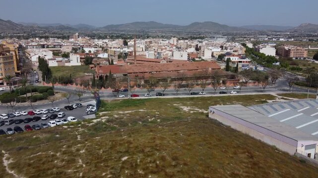 Drone footage zooming in on abandoned historical factory buildings at the entrance of Aspe, Alicante, Spain. Aerial view of rustic industrial heritage and urban architecture.