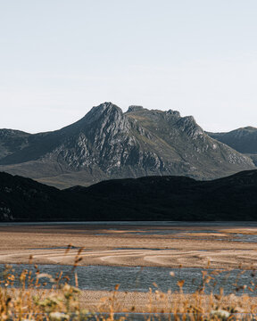 View of Ben Loyal rising above the expansive sandy tidal flats and rugged landscape in Lairg, Scotland, United Kingdom.