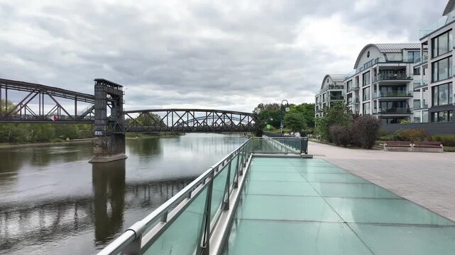 Elbe riverfront promenade in Magdeburg, view from Elbbalkon (Elbe Balcony) to vertical-lift bridge, wide angle time-lapse with motion blur of people, Saxony-Anhalt, Germany