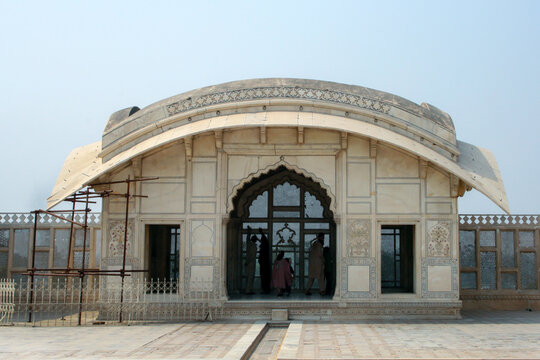 View of the historic Naulakha Pavilion at Lahore Fort with its distinctive curved roof, intricate marble carvings, and people visiting the site in Lahore, Punjab, Pakistan.