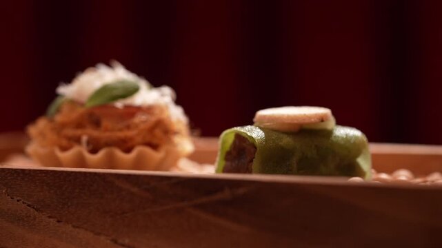 Gourmet appetizers served on a wooden tray with a dark red background for fine dining presentation