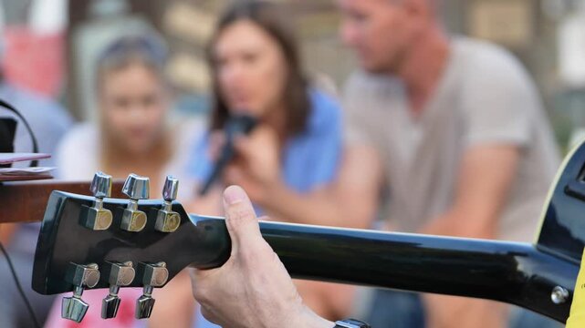 Musician playing guitar for blurred audience, performing live music outdoors at a farm