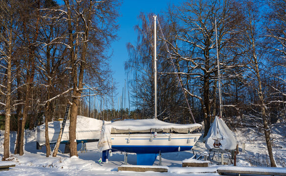 View of sailboats covered for winter storage in a snowy forest clearing in Trakai, Vilnius County, Lithuania.