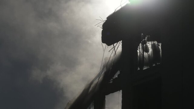 Artistic view of a crane demolishing a multi-story building in sunny weather.