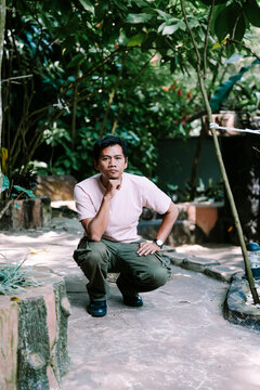 Man Crouching in a Lush Green Garden