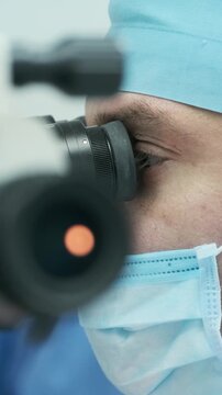 Professional ophthalmologist performing cataract removal and intraocular lens (IOL) implantation under a surgical microscope in an operating room.
