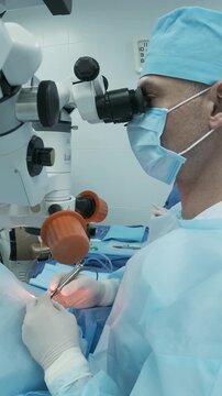 Professional ophthalmologist performing cataract removal and intraocular lens (IOL) implantation under a surgical microscope in an operating room.