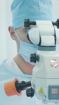 Professional ophthalmologist performing cataract removal and intraocular lens (IOL) implantation under a surgical microscope in an operating room.