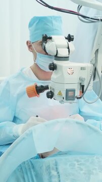 Professional ophthalmologist performing cataract removal and intraocular lens (IOL) implantation under a surgical microscope in an operating room.