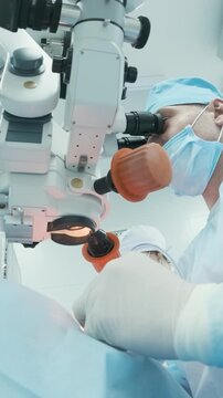 Professional ophthalmologist performing cataract removal and intraocular lens (IOL) implantation under a surgical microscope in an operating room.