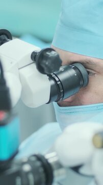 Professional ophthalmologist performing cataract removal and intraocular lens (IOL) implantation under a surgical microscope in an operating room.