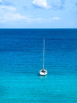 View of a sailboat floating in the clear turquoise waters off the coast of the Island of Favignana, Favignana, Sicily, Italy.
