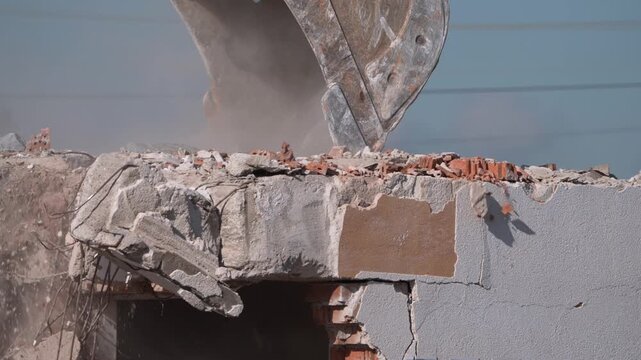 A crane demolishing a multi-story building in sunny weather.