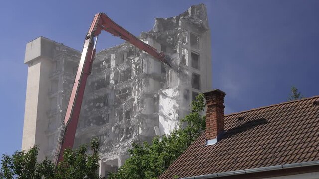 A crane demolishing a multi-story building in sunny weather.