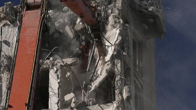 A crane demolishing a multi-story building in sunny weather.