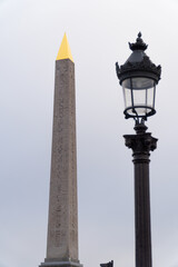 Fototapeta premium L'Obélisque de Louxor avec sa pointe dorée et un réverbère traditionnel parisien, Place de la Concorde à Paris, France.